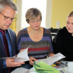 MdL Horst Wehner, Frau Roth und Janina Pfau schauen in eine Broschüre der Elterninitiative