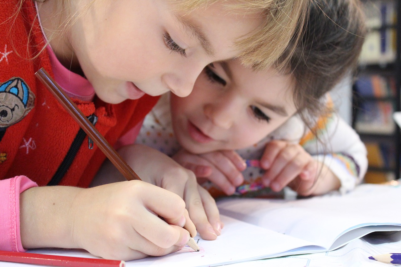 Zu sehen sind zwei Schulkinder, die zusammen arbeiten.